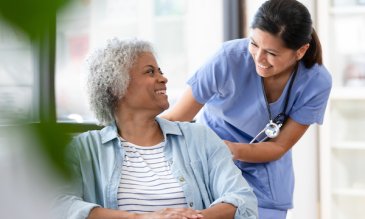 Nurse smiling at a patient in a wheelchair