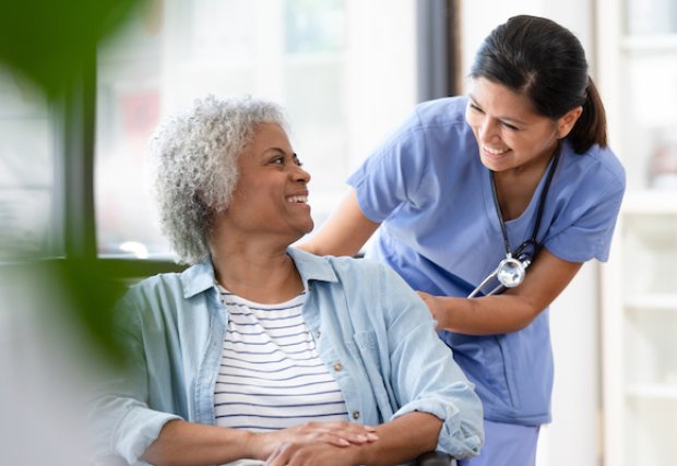 Nurse smiling at a patient in a wheelchair