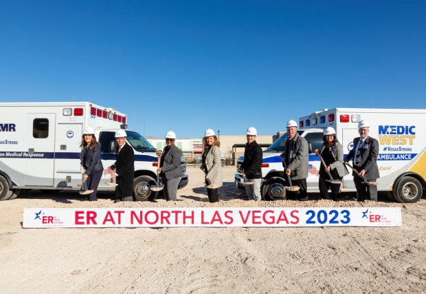 Group poses who tossed dirt on groundbreaking for Valley ER at North Las Vegas in front of sign that says coming late 2023