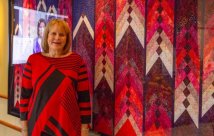 Lois DeGiulio standing in front of her homemade quilt